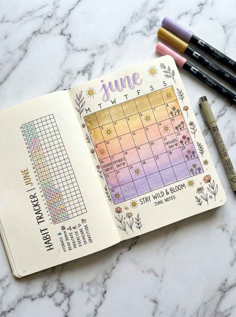 June bullet journal spread with sunset watercolor gradient background, hand-lettered ink grid, and floral margin doodles beside a habit tracker page