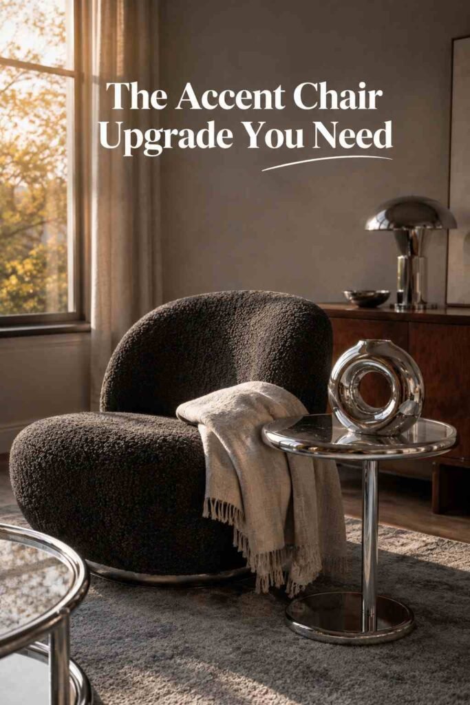 Charcoal bouclé accent chair beside a small chrome side table with a sculptural object and a linen throw.