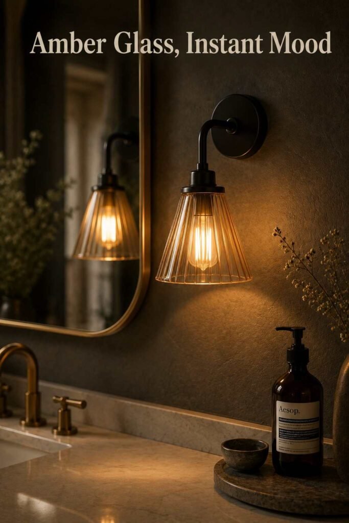 Close-up of a black iron sconce with an amber glass shade glowing warmly.
