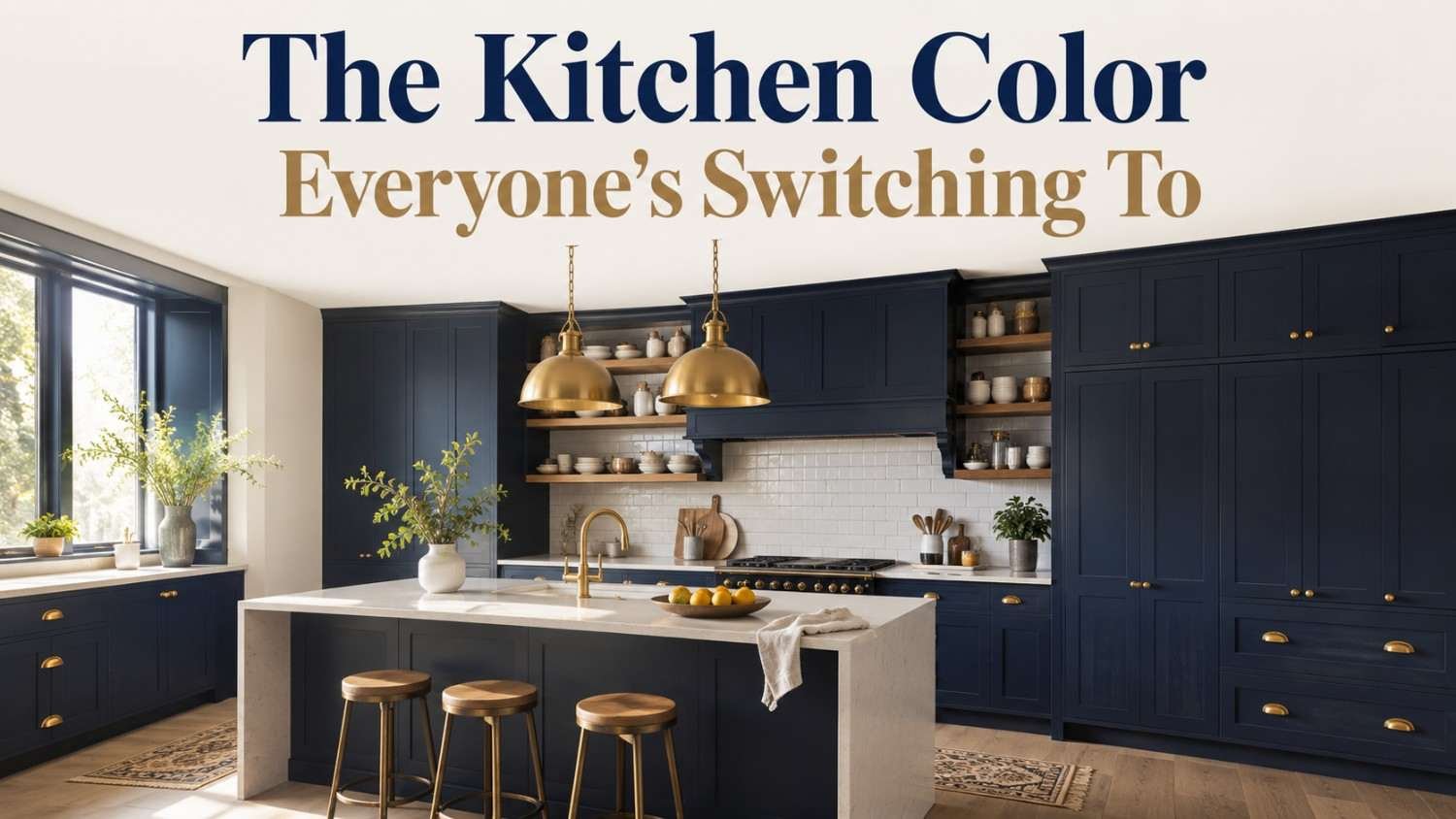 Navy blue kitchen with brass hardware, white quartz waterfall island, and open oak shelving.