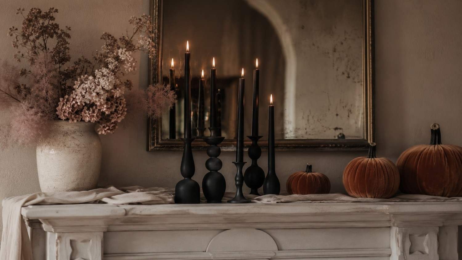 Chic Halloween aesthetic mantel with black candles, blush dried florals and muted pumpkins