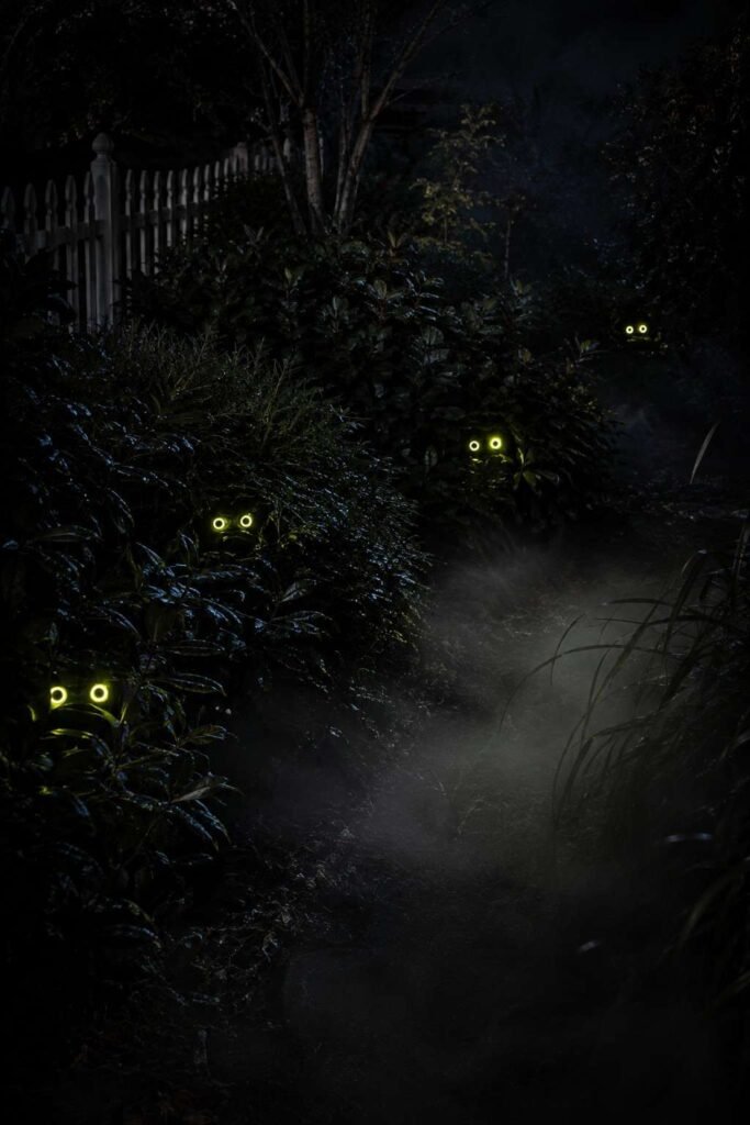 28 Halloween Party Decorations Scary Enough to Terrify Every Guest 4 Pairs of glowing eyes hidden in garden bushes at night as outdoor scary Halloween decorations.