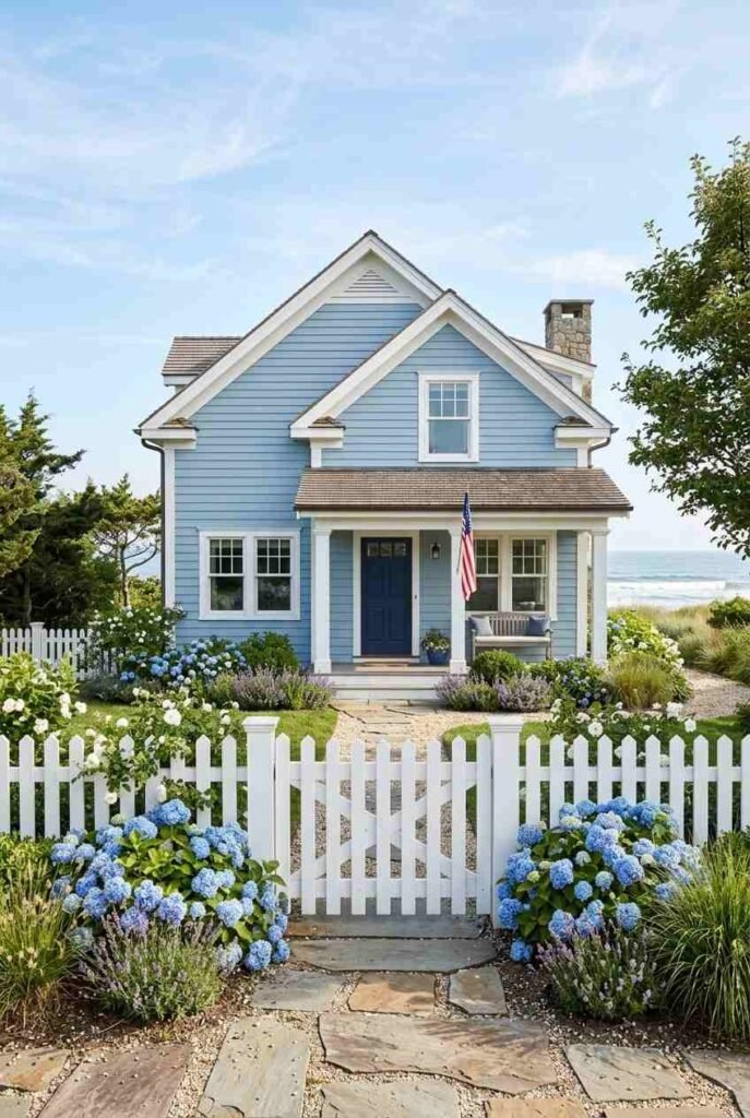 Powder blue beach cottage with white trim, navy door, and hydrangeas